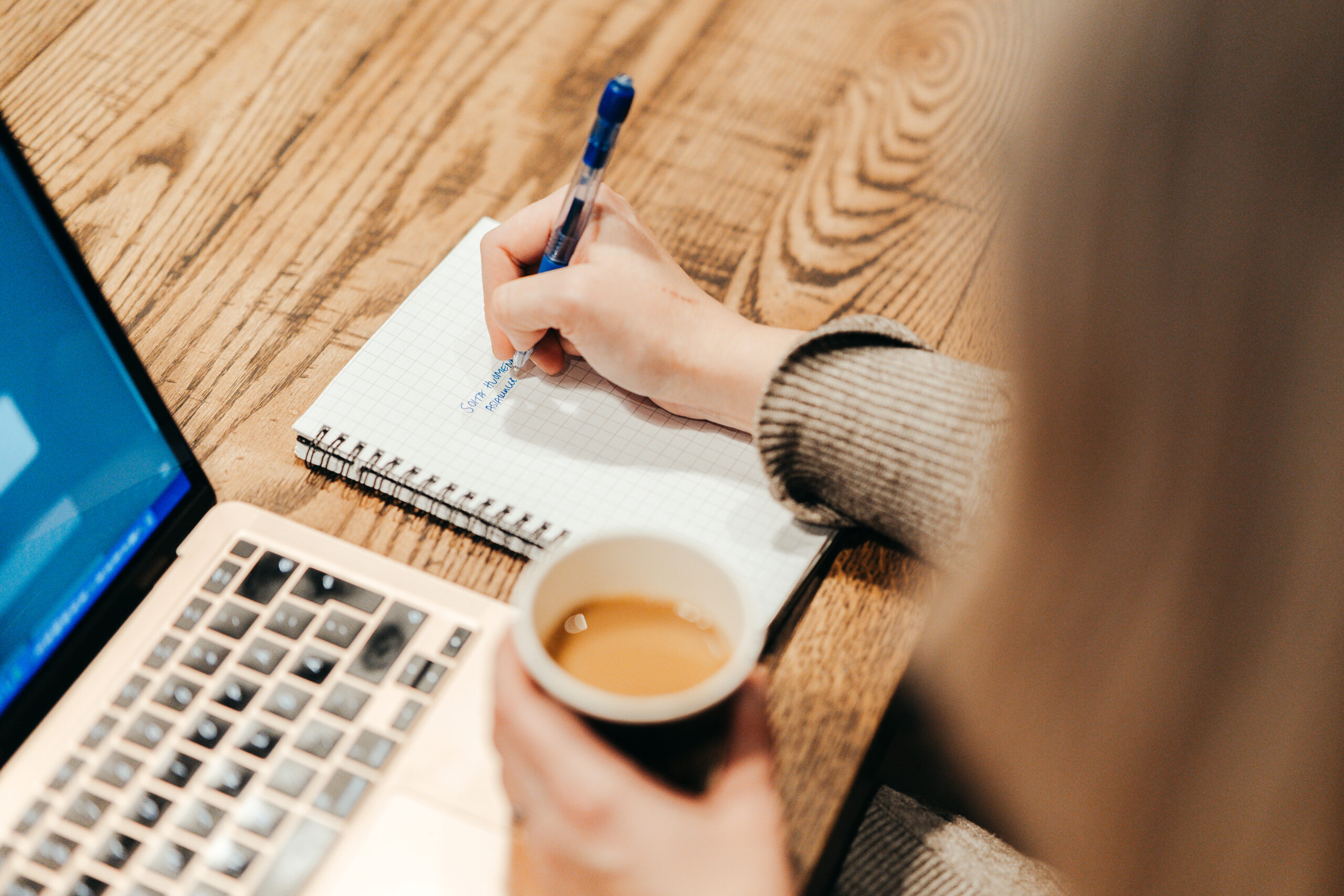 Ulkoistettu projektipäällikkö suunnittelemassa markkinointiprojektia muistiinpanojen ja kannettavan tietokoneen äärellä.