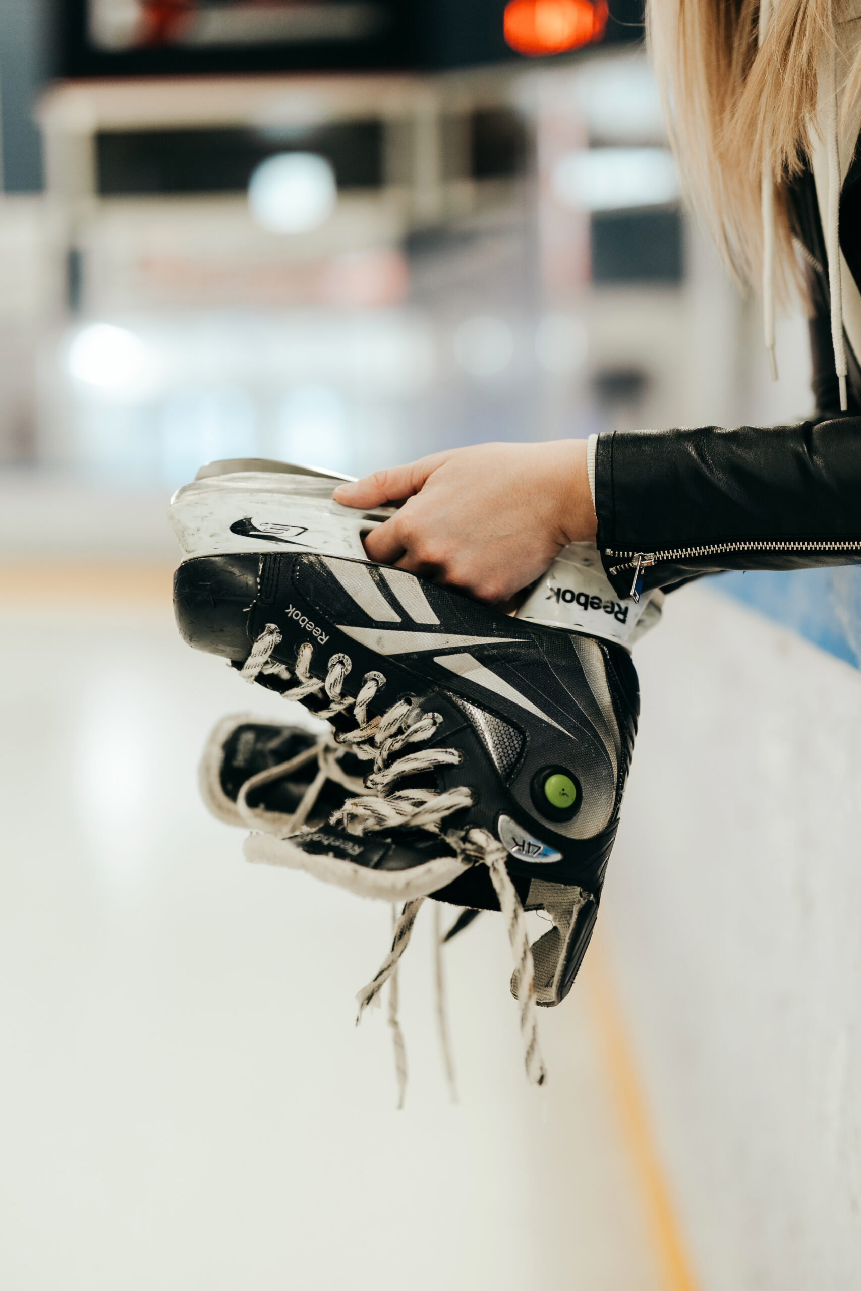 Markkinoinnin ja myynnin yhteensovittamiseen erikoistuneen asiantuntijan kädet pitelemässä jääkiekkoluistimia jäähallissa, symboloiden roolia yrityksen tulkkina ja yhteistyön rakentajana.